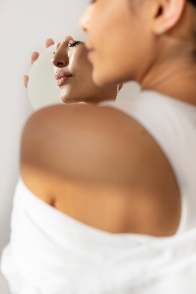 Femme observant son visage dans un miroir après un soin de dermatologie esthétique à Paris